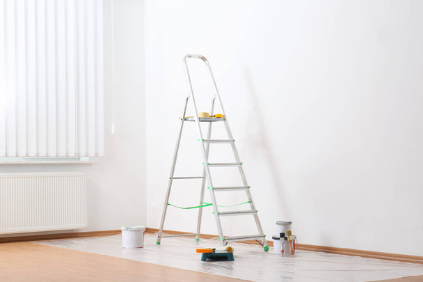Stepladder and painting tools near wall in empty room - Foto, immagini