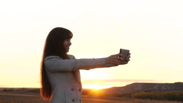 Touristin macht Selfie mit Tablet Die schöne Geschäftsfrau ist unterwegs und macht vor dem Hintergrund des Sonnenuntergangs ein Selfie-Foto mit dem Handy. Tourismuskonzept - Foto, Bild