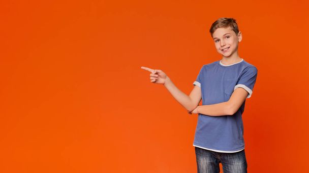 Little boy pointing away on orange background - Photo, Image