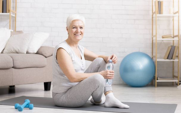 Senior woman resting on exercise mat after fitness workout - Photo, Image