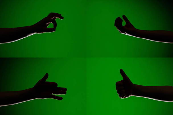 Um conjunto de caracteres nos dedos das mãos humanas que são representados por silhuetas em um fundo verde isolado
 - Foto, Imagem