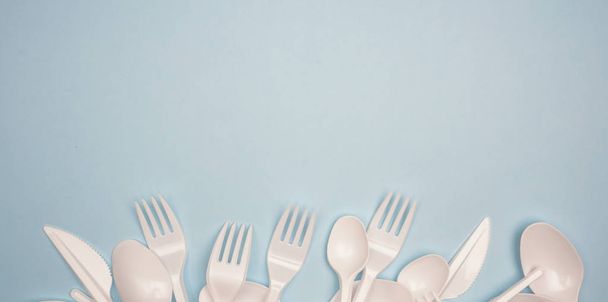 Single-use plastic products: plastic cutlery, cups on bright blu - Фото, зображення