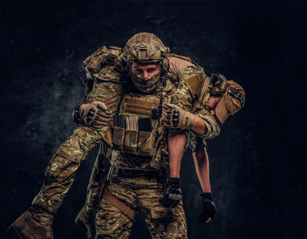 Боевой конфликт, специальная миссия, отступление. Солдат спецназа спасает раненого товарища по команде, несущего его с поля боя на плечах.
. - Фото, изображение