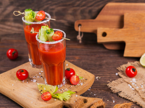Two glasses of tomato juice decorated with fresh tomatoes, cucum - Fotó, kép