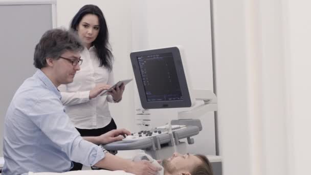 Doktor dělá ultrazvukové diagnostiky a sestra opraveny informace na tablet - Záběry, video