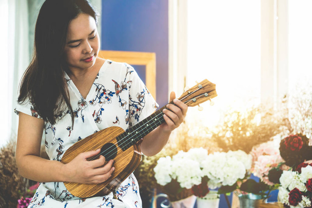 Mulher feliz músico tocando ukulele no estúdio
. - Foto, Imagem