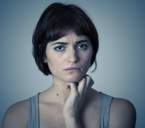 Close up of a young sad woman, serious and concerned, looking worried in emotional pain. Feeling sorrow and depression. Isolated in neutral background. In facial expressions and emotions concept. - Fotó, kép