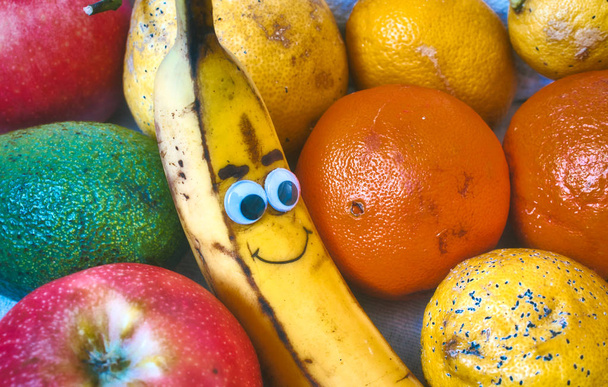 eine Schüssel mit frischem Obst mit einer Smiley-Banane mit einem frechen Gesicht - Foto, Bild