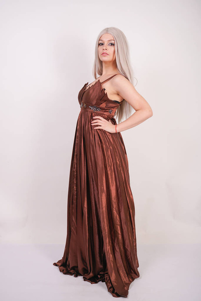 gorgeous young woman with white hair in brown long evening dress on white background in Studio alone - Фото, зображення