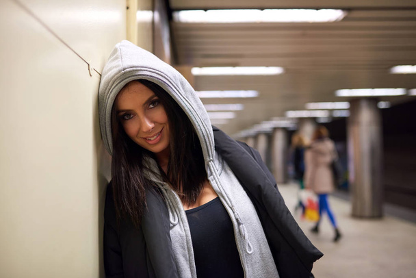 A smiling young woman standing at a subway station - Фото, изображение