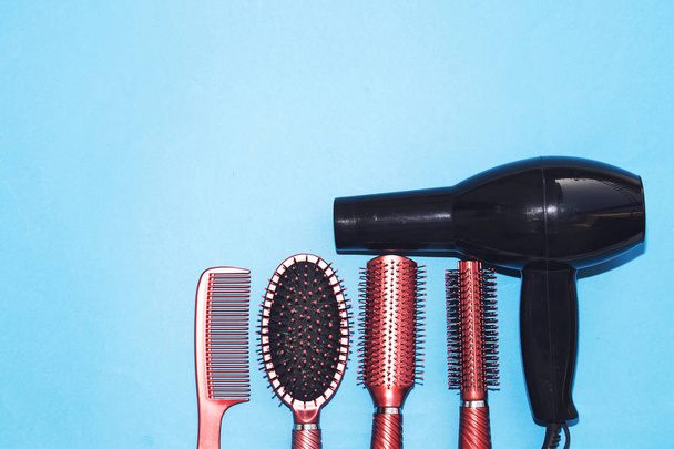 Профессиональные инструменты для парикмахерской и черный фен на синем фоне с копировальным пространством - Фото, изображение