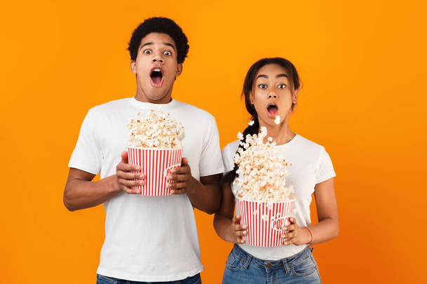 Horror film. Frightened couple throwing popcorn over background - Fotografie, Obrázek
