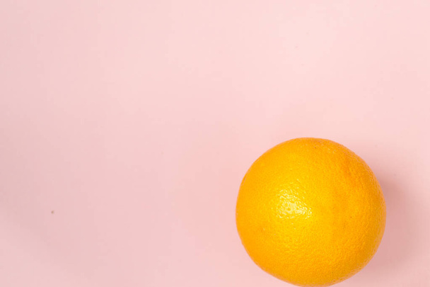 Isolated orange orange against a pink background - Foto, Bild