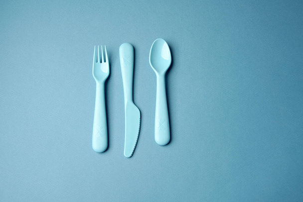 Blue plastic dishes on blue background. Concept - Zdjęcie, obraz