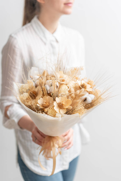 beautiful bouquet of mixed dried flowers in woman hand. the work of the florist at a flower shop. Delicate Pastel tones color - Photo, image