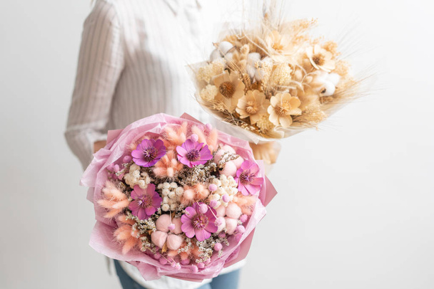 Dwa piękne bukiety kwiatów suszonych mieszane w ręce kobiety. Praca w kwiaciarni Kwiaciarnia. Delikatne pastelowe odcienie kolorów - Zdjęcie, obraz