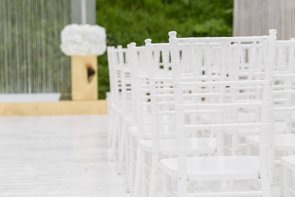 Sorok üres fehér szék ül a fa padló. Esküvői virágok a szertartást a szabadban szék - Fotó, kép