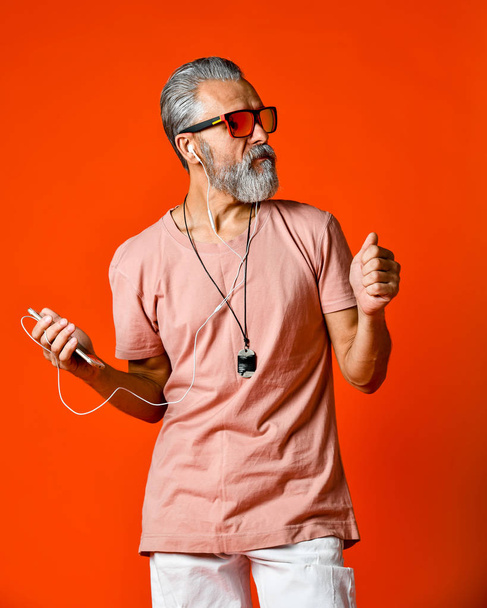 An image of an elderly bald head man listening to music with headphones - Fotó, kép