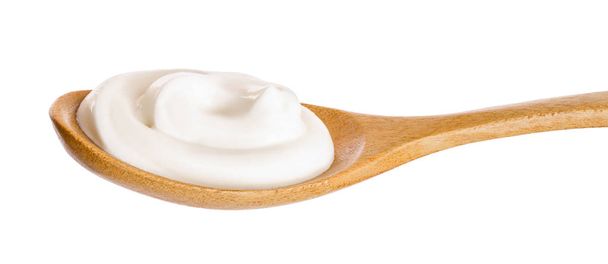 Crema agria en cuchara de madera aislada sobre fondo blanco - Foto, Imagen