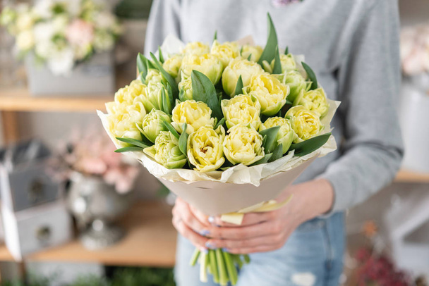 Jovem mulher bonita segurando um buquê de primavera de tulipas amarelas em sua mão. Bando de flores frescas de primavera cortadas em mãos femininas
 - Foto, Imagem