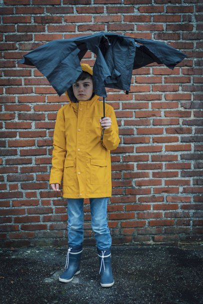 boy standing under teared up umbrella - Fotografie, Obrázek