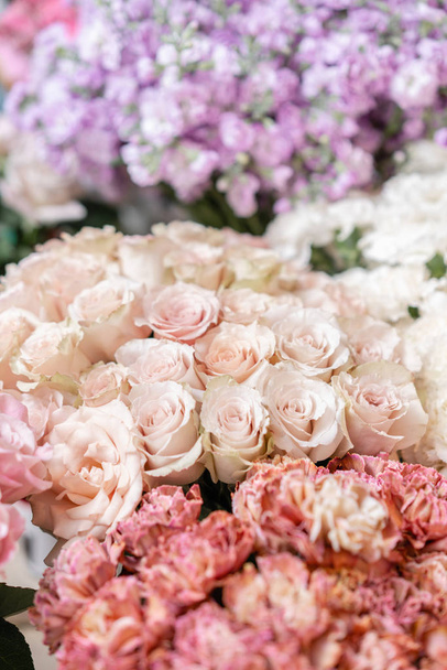 Floral carpet, flower texture, shop concept. Beautiful fresh blossoming flowers roses, spray roses, lilac gillyflower and carnation. Blossom of pastel color in vases and pails. Top view. - Foto, imagen