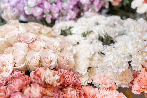 Floral carpet, flower texture, shop concept. Beautiful fresh blossoming flowers roses, spray roses, lilac gillyflower and carnation. Blossom of pastel color in vases and pails. Top view. - Photo, Image