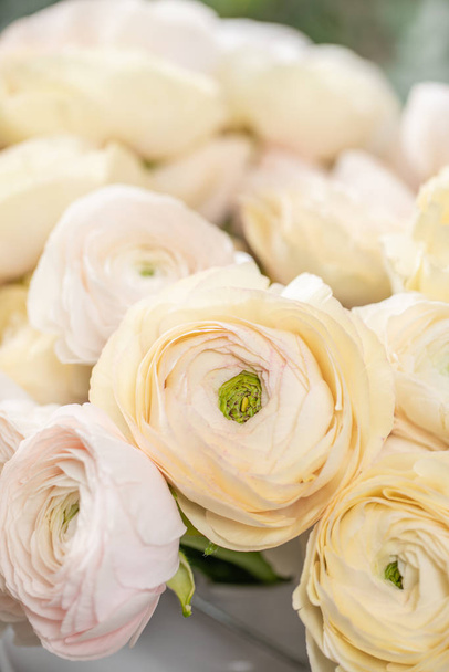 Perzsa buttercup. Csomó a halvány rózsaszín, és pasztell sárga ranunculus virágok vázában üveg. Függőleges tapéta - Fotó, kép
