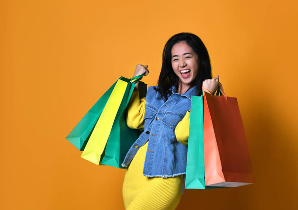 Young asian woman with shopping bags on color background - Photo, image