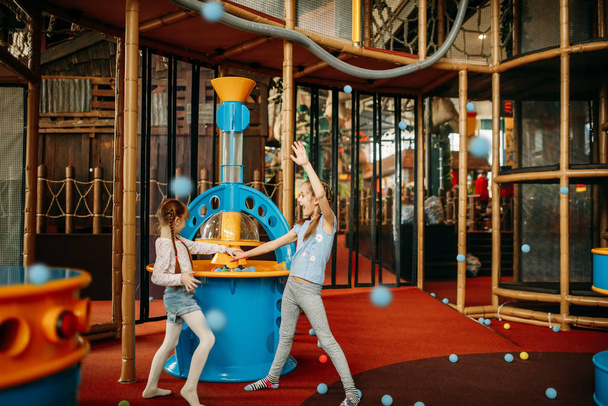 Dvě malé holčičky hraje Airsoft stroj v herním centru dětí. Vzrušený děti baví na hřiště uvnitř. Děti hrají v zábavním centru - Fotografie, Obrázek