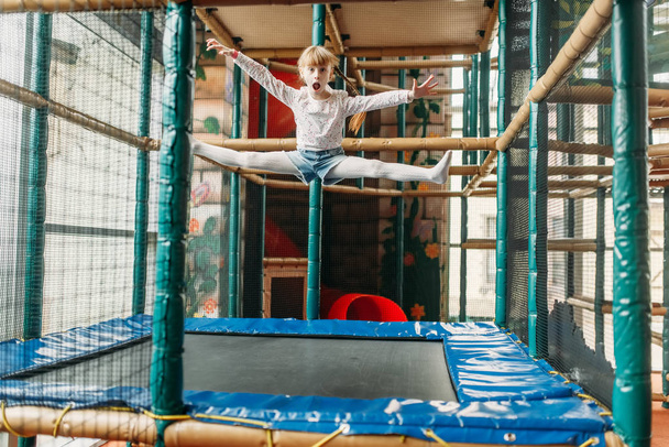 Zabawna dziewczyna skoki na trampolinie, dzieci centrum gry. Podekscytowany dziecko bawiąc się na placu zabaw w pomieszczeniu - Zdjęcie, obraz
