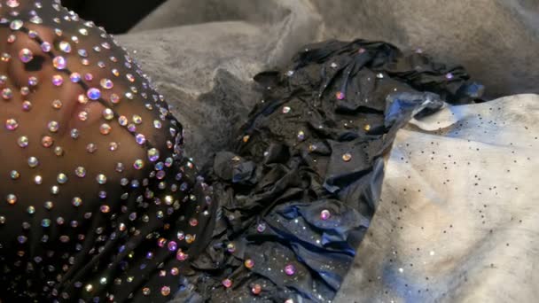 Wysoka moda. Projektant przygotowuje wizerunek modelu obcy dziewczyna w czarnej maski w dżetów musujące, błyszczy, metalowe motyle w Studio w - Materiał filmowy, wideo