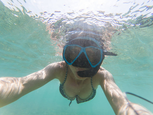 женщина делает подводное селфи во время плавания с маской и трубкой в кристалле CL
 - Фото, изображение
