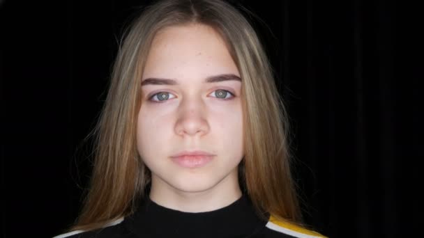 Portret van een mooie jonge tiener meisje met lang wit haar en groene ogen poseren voor de camera in de studio op een zwarte achtergrond - Video