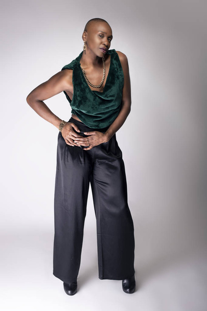 Black African American female fashion model posing with trendy bald hairstyle and stylish clothing in a studio.  She is looking confident and showing beautiful individuality. - Foto, immagini