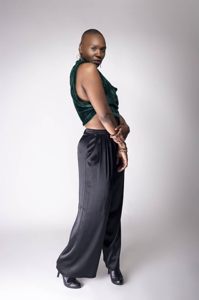 Black African American female fashion model posing with trendy bald hairstyle and stylish clothing in a studio.  She is looking confident and showing beautiful individuality. - Photo, image
