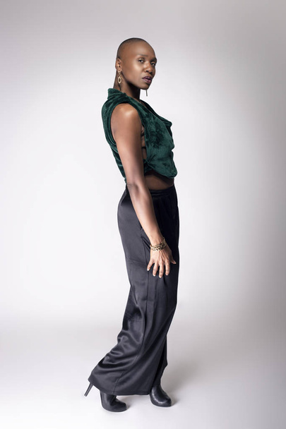 Black African American female fashion model posing with trendy bald hairstyle and stylish clothing in a studio.  She is looking confident and showing beautiful individuality. - Valokuva, kuva
