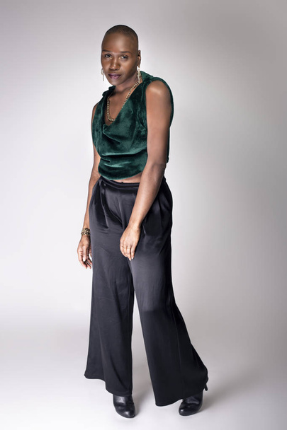 Black African American female fashion model posing with trendy bald hairstyle and stylish clothing in a studio.  She is looking confident and showing beautiful individuality. - Foto, immagini
