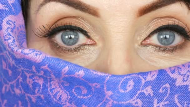 Portret arabskiego w średnim wieku dorosłego kobieta z niezwykłą piękne duże niebieskie oczy z długimi rzęsami w tradycyjnym islamskim nikab tkaniny lub burki. Bliska pięknej muzułmańskiej kobiety - Materiał filmowy, wideo