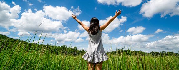 Mujer joven sobre hierba verde extendiendo los brazos al cielo
. - Foto, Imagen