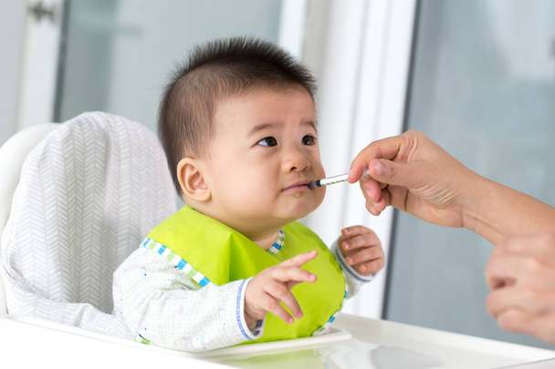 Mamá está alimentando medicina líquida a su hijo asiático
 - Foto, Imagen