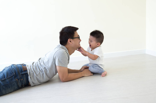 Azjatycka ojciec i syn gry i uśmiecha się na piętrze w pokoju, rodziny posiadające koncepcja zabawa i śmiech - Zdjęcie, obraz