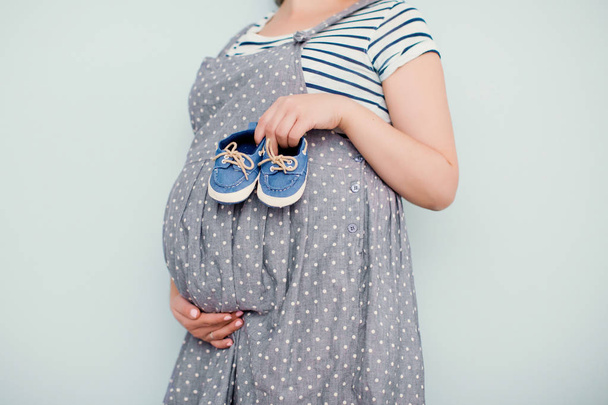 mulher grávida com sapatos de bebê pequeno
 - Foto, Imagem