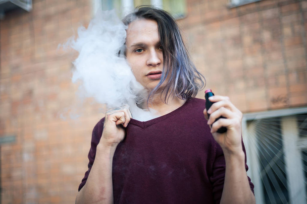 Portrait of a young man in the smoke of cigarettes - Photo, Image