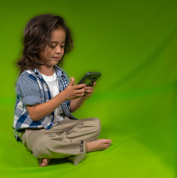 un selfie garçon cheveux longs avec son mobile sur fond vert
 - Photo, image