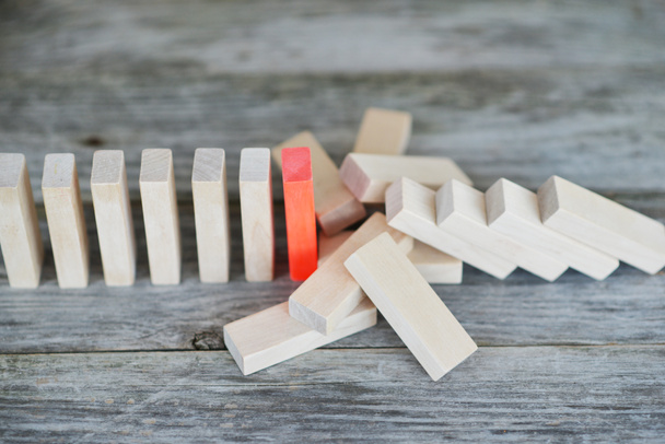 Peça vermelha de dominó resistindo ao efeito dominó, impedindo a queda da linha
 - Foto, Imagem