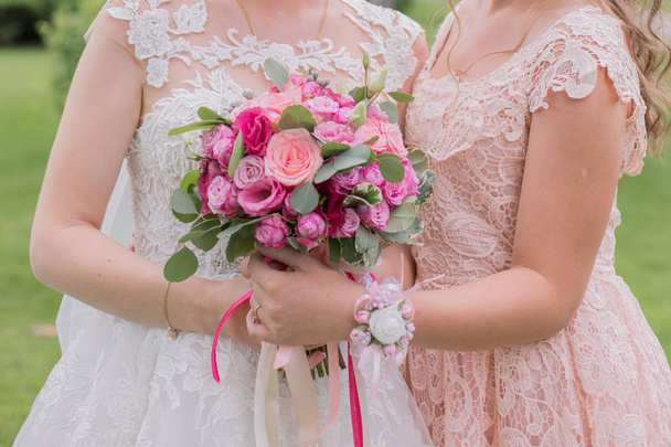 bride with bridesmaid and wedding bouquet in the park - Fotografie, Obrázek