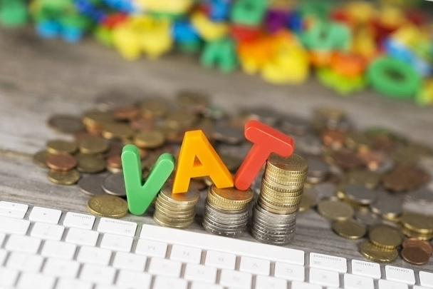 Pojęcie wzrostu podatku od wartości dodanej z VAT słowo z tworzyw sztucznych listów na monetach ułożone jako wykres na drewnianym stole  - Zdjęcie, obraz
