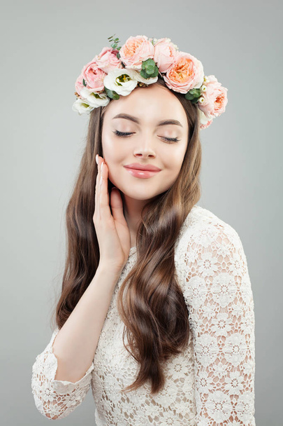 Modelo de mulher perfeita com cabelo encaracolado, maquiagem e flores
.  - Foto, Imagem