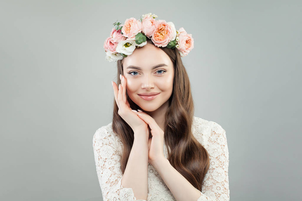 Χαριτωμένο μοντέλο γυναίκα με μακριά μαλλιά, μακιγιάζ και ανοιξιάτικα λουλούδια χαμογελώντας σε γκρίζο φόντο - Φωτογραφία, εικόνα